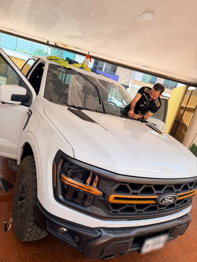 Instalador polarizando el parabrisas de una Ford F-150 Tremor blanca en una cochera