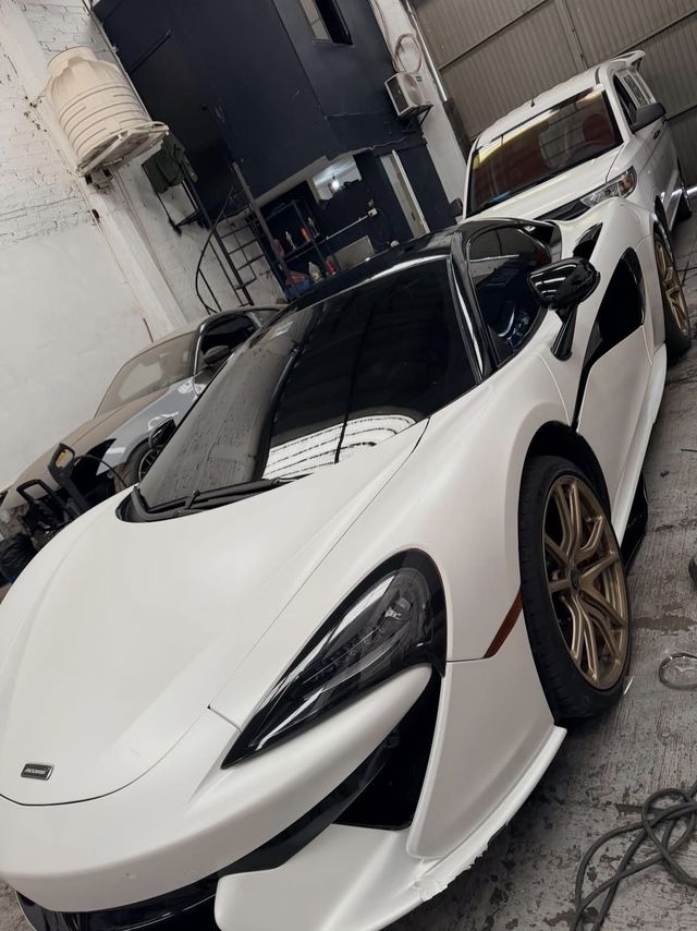 McLaren blanco mate con rines dorados y cristales polarizados oscuros
